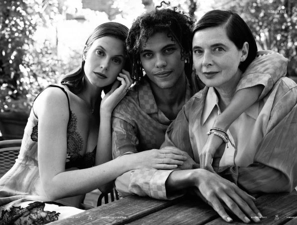 Monochrome portrait of three models posing together at an outdoor wooden table with makeup by Chris Colbeck