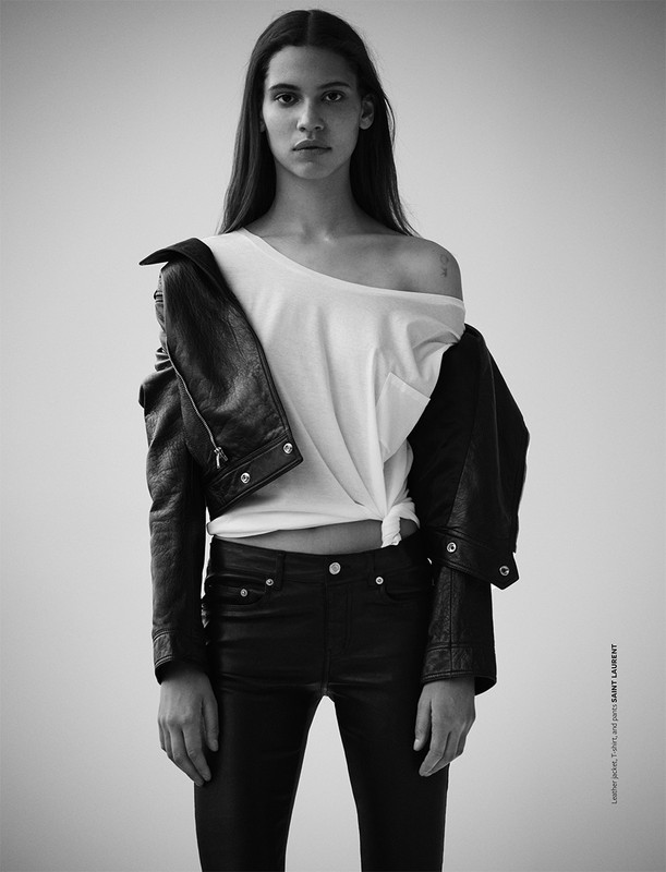 Portrait of a young adult female fashion model in a white shirt and black leather jacket against a neutral background in black and white.