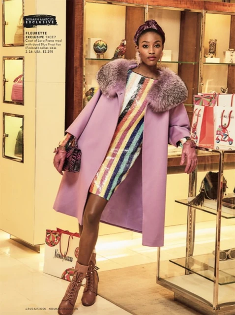 Elegant woman in a lilac coat and colorful sequin dress holds a purse. She wears heeled shoes, gloves, and a hair accessory indoors.