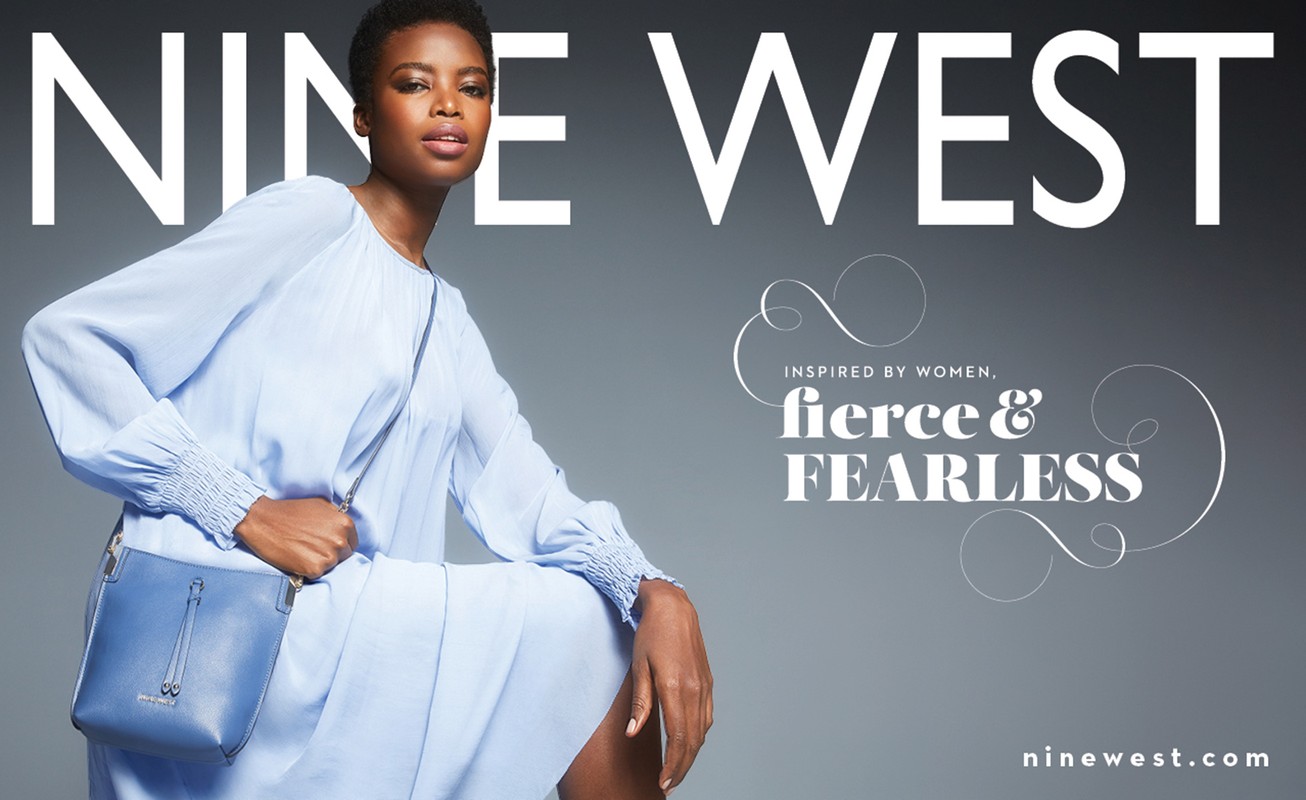 Nine West campaign image featuring an African American woman in a light blue dress and matching purse, posing against a grey background.
