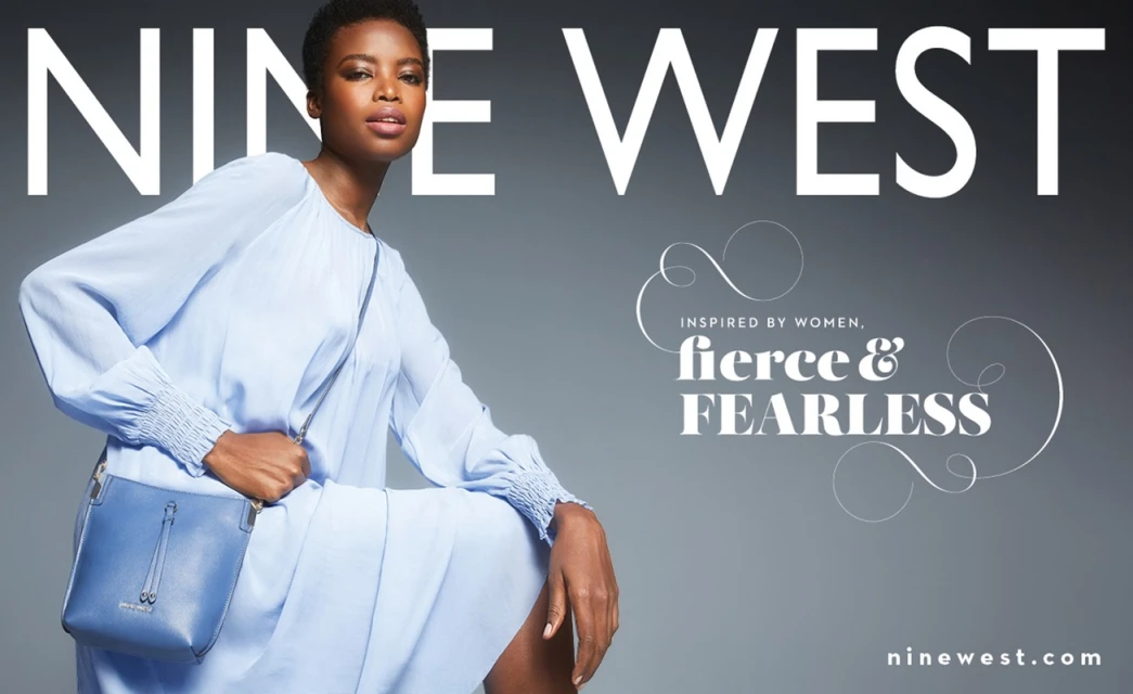 Nine West campaign image featuring an African American woman in a light blue dress and matching purse, posing against a grey background.