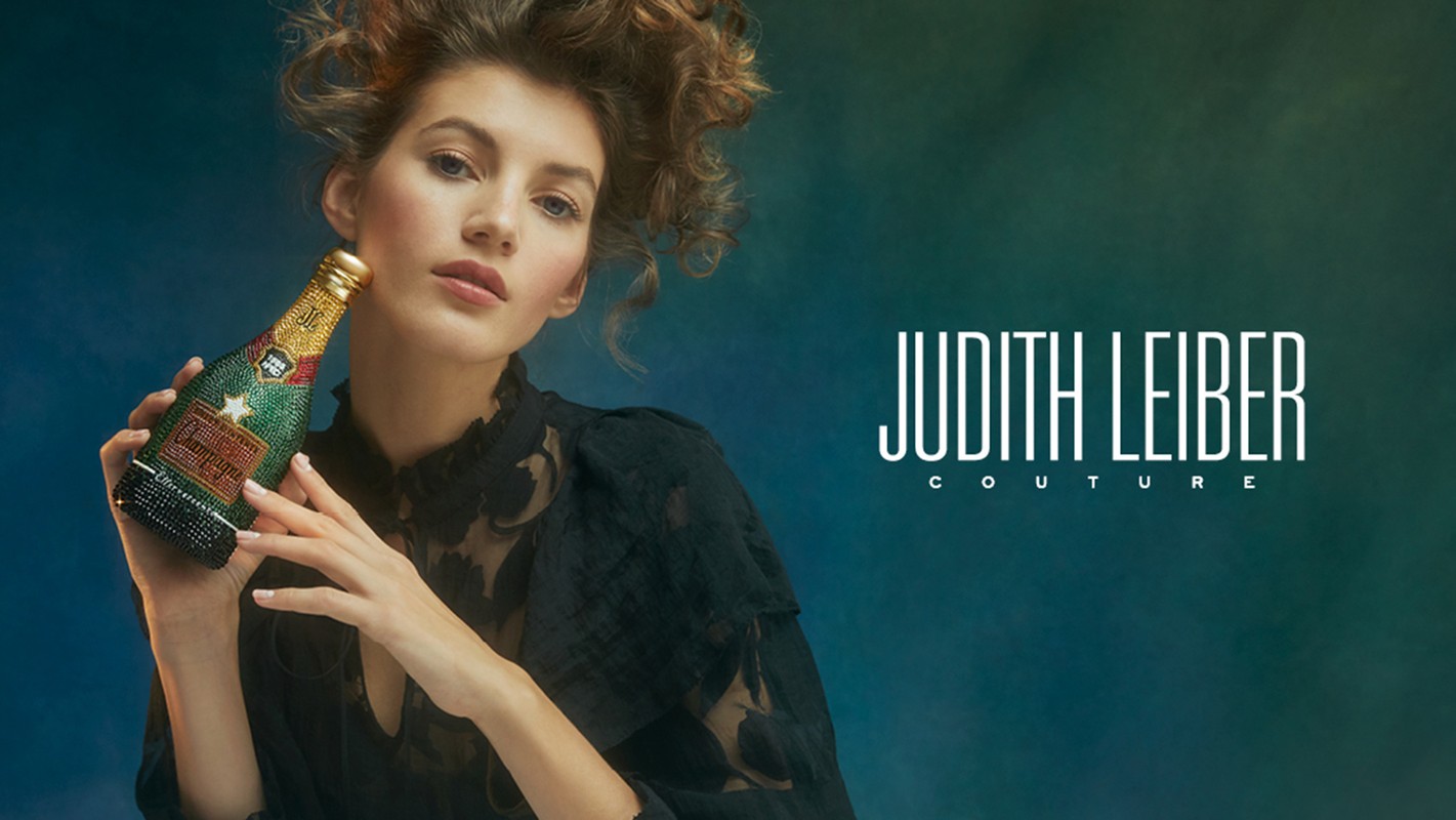 Elegant woman holds a crystal embellished Champagne bottle purse by Judith Leiber Couture in a fashion forward studio portrait.