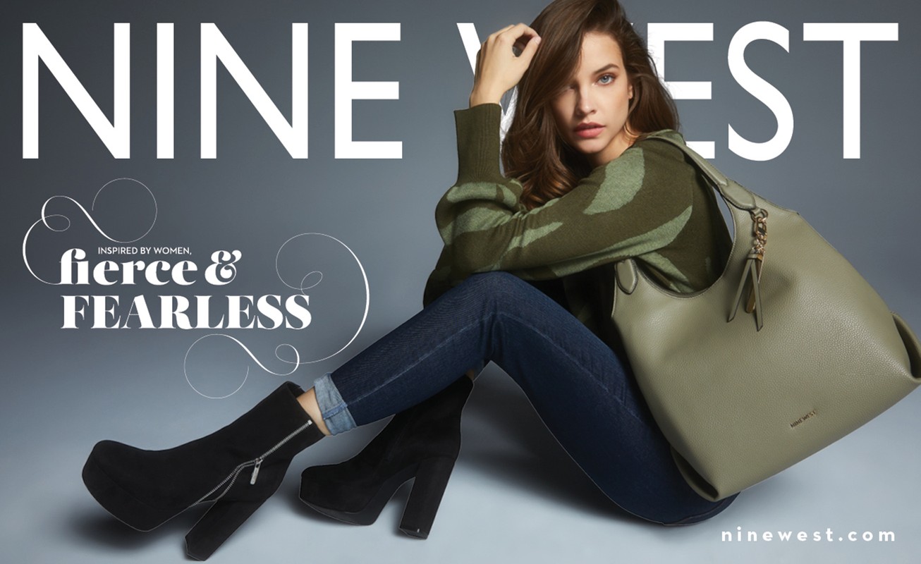 Fashion ad featuring a woman wearing a patterned sweater, jeans, and heeled boots, holding a large Nine West handbag in a studio setting.