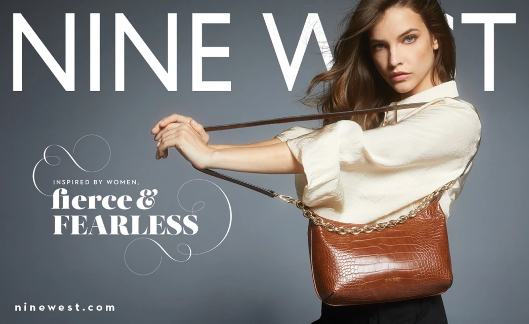 Nine West ad featuring woman with shoulder bag. The purse has a thick metal chain and crocodile texture. Neutral background, studio lighting.