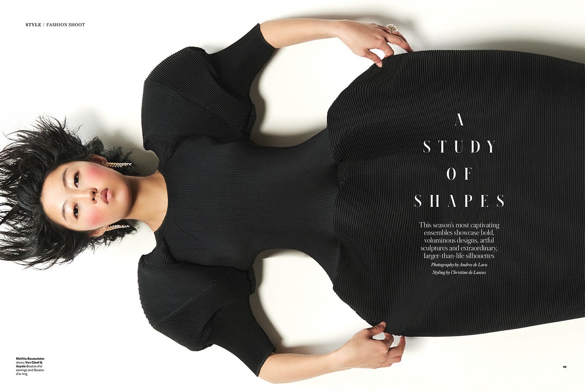 Fashion editorial photo featuring an Asian woman in a black dress on a white backdrop, styled for a studio fashion shoot. 