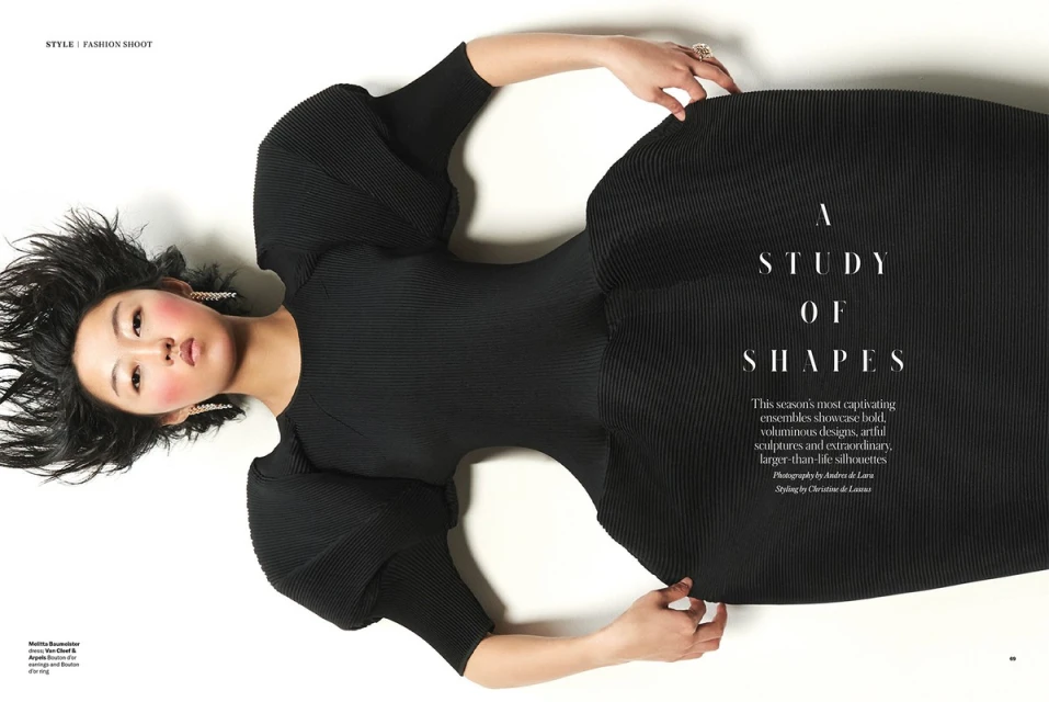 Fashion editorial photo featuring an Asian woman in a black dress on a white backdrop, styled for a studio fashion shoot. 
