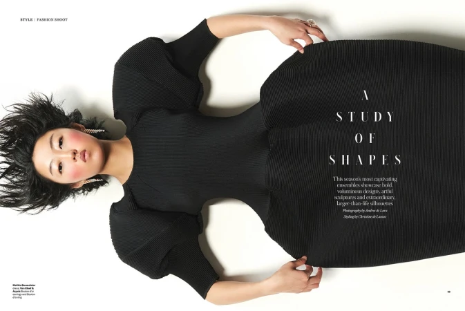 Fashion editorial photo featuring an Asian woman in a black dress on a white backdrop, styled for a studio fashion shoot. 