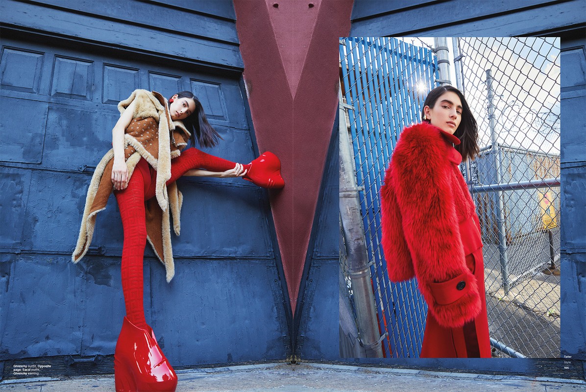 Two fashion models pose outdoors in front of blue metal doors, one in a brown coat and red leggings and the other in red fur coat.