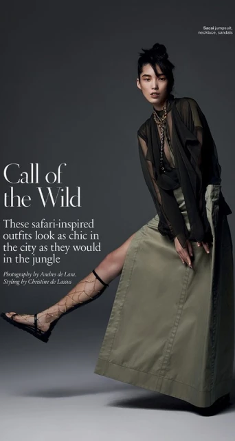 Editorial fashion shot of an Asian woman in a semi-sheer top and olive maxi skirt, accessorized with a gold necklace and leg jewelry.
