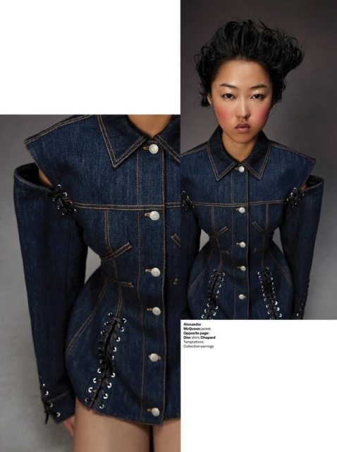 An Asian woman wears a dark-denim jacket with unique shoulder cutouts and corset-style lace-up detail, posing against a gray background.