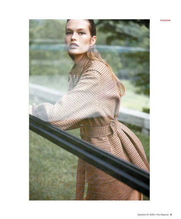 Model in brown houndstooth belted coat leaning against a railing in an outdoor park setting styled by Christine De Lassus