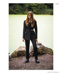 Model standing outdoors near a pond wearing a black blazer and trousers styled by Christine De Lassus