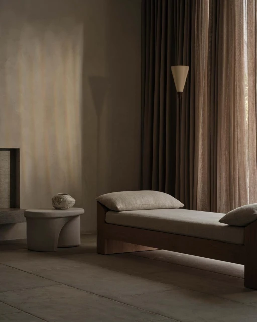 Minimalist interior with a daybed, side table with vase, neutral color palette, and soft lighting, creating a serene and inviting atmosphere.
