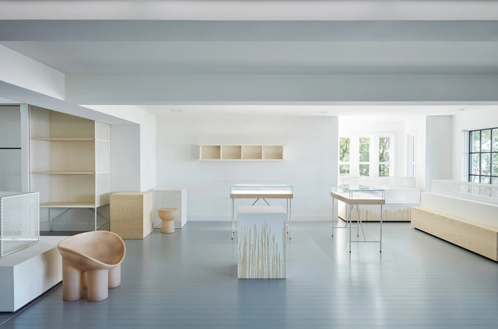 Minimalist retail space showcases modern furniture, display cases, and architectural shelving in a clean, brightly lit interior.