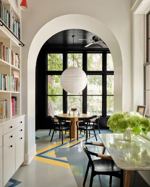 Bright, airy dining room with modern furniture: round table, black chairs, marble-top console, and patterned flooring, flooded with natural light.