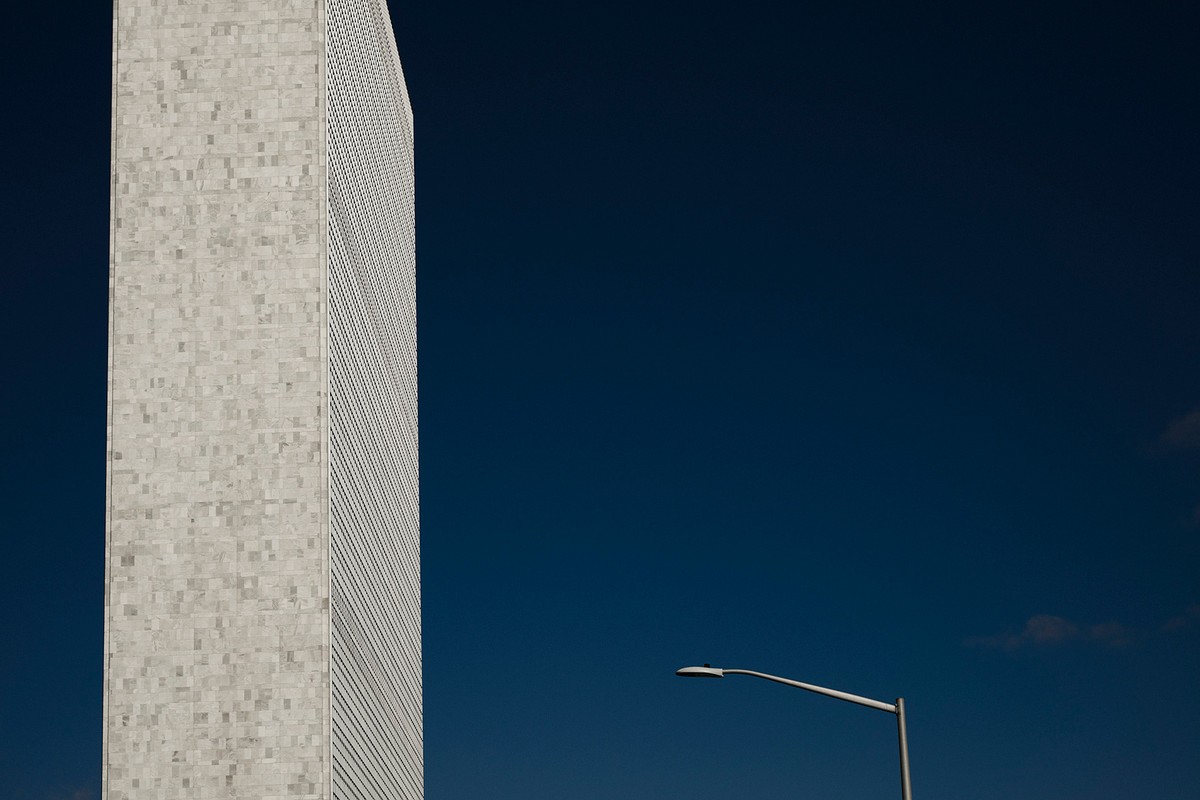 Architectural shot of a tall building with a square-patterned facade under a deep blue sky, next to a streetlight.