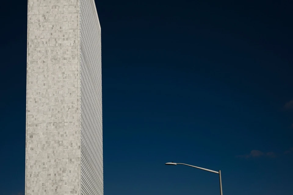 Architectural shot of a tall building with a square-patterned facade under a deep blue sky, next to a streetlight.