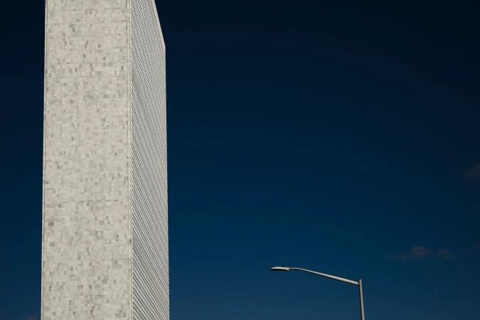 Architectural shot of a tall building with a square-patterned facade under a deep blue sky, next to a streetlight.