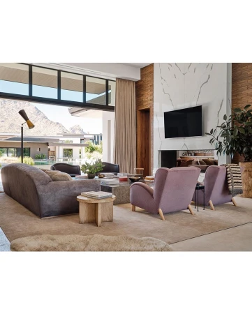 Living room interior showcasing a gray sofa, two pink armchairs, and a marble fireplace with a mounted TV in a modern home setting.