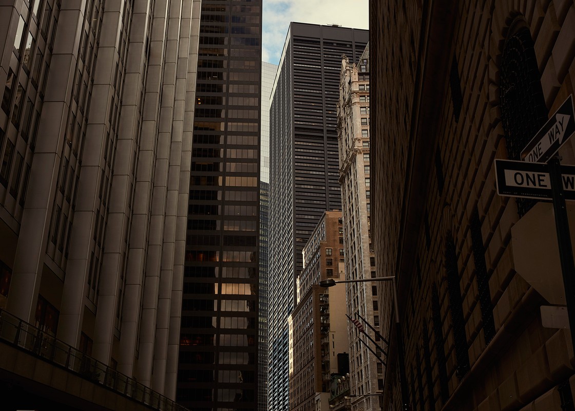 Urban landscape featuring a view between tall buildings, showcasing architectural details and a sense of depth in a city environment.