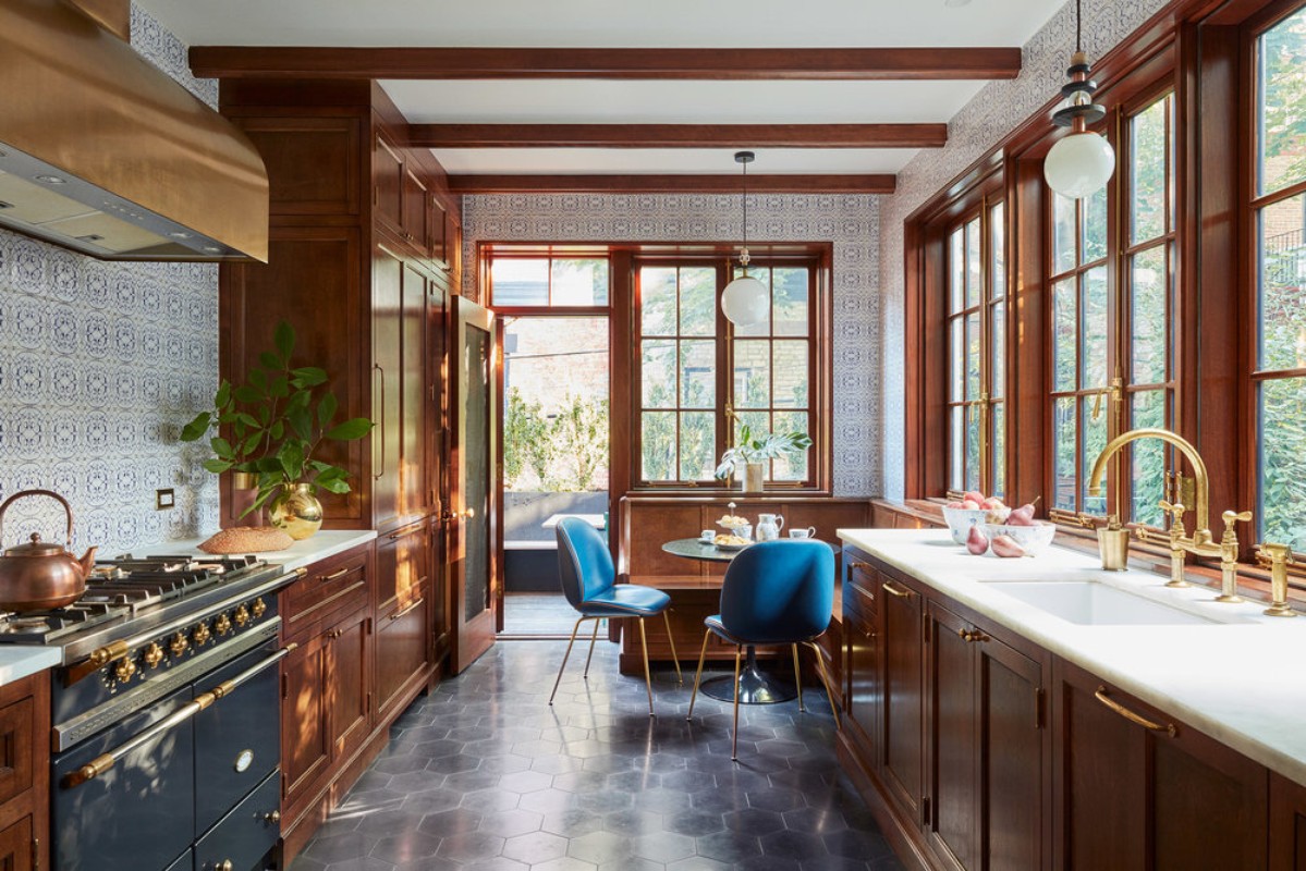A home interior view of a kitchen with dark wood cabinets, white countertops, blue chairs around a table, and a range oven.