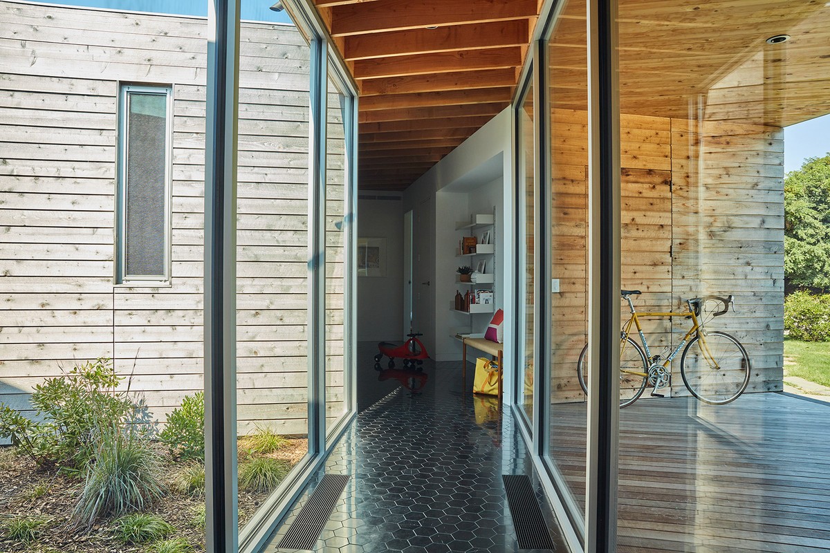 Hallway view through large glass doors and windows, showcasing wooden walls, a bicycle, and interior decorations.