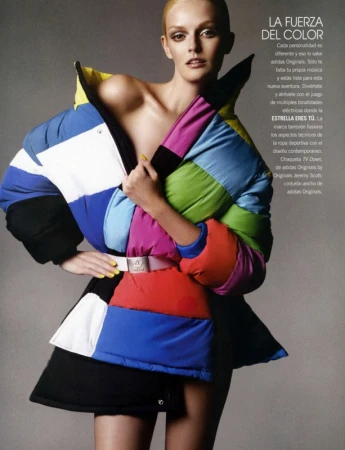Model wearing a vibrant color-blocked puffer jacket with a white belt against a grey studio backdrop.