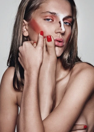 Close-up portrait of a woman with bold colorful makeup pressing her foot against her face by Christopher Ardoff