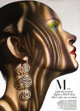 Profile portrait of a woman wearing hanging diamond earrings with zebra-stripe patterned light cast across her face.
