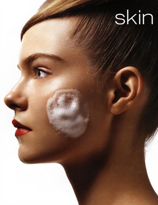 Profile of woman with red lipstick and facial cleanser. Shot in a photo studio against a white background. Beauty advertising concept.