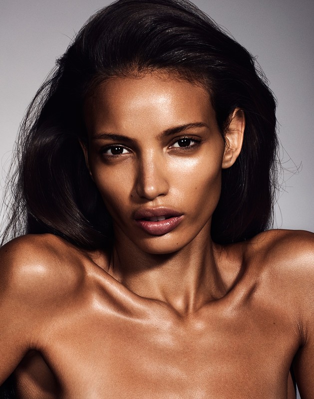 Close-up portrait of a woman with long black hair and tan skin in a beauty style, posing in a photo studio with neutral background.