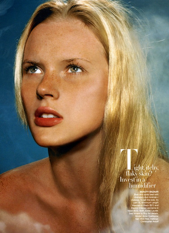 Beauty shot featuring a fair-skinned, blonde adult female model with freckles, soft lighting, and a blue and white gradient background.