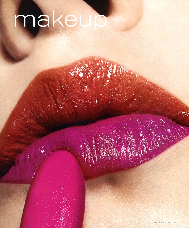 Close-up of a woman's face with vivid red and fuchsia lipstick applied on her lips. A lipstick tube is used to apply the makeup.