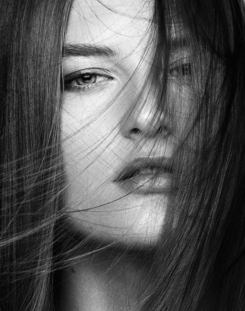 Close-up black and white portrait of a woman with long hair falling across her face by Christopher Ardoff