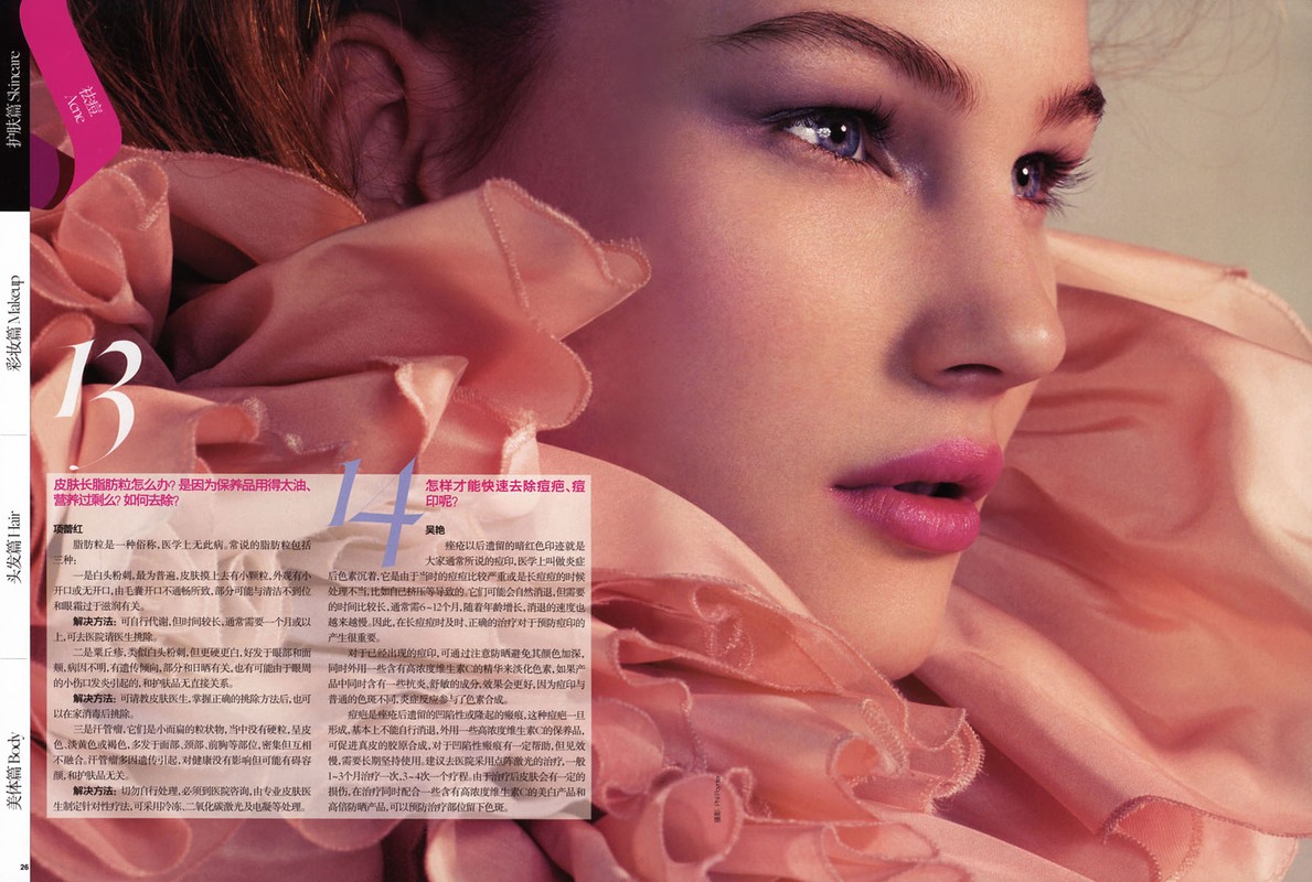 Close-up beauty shot of a fair-skinned young woman with blue eyes and pink lipstick, framed by a large pink ruffled collar.
