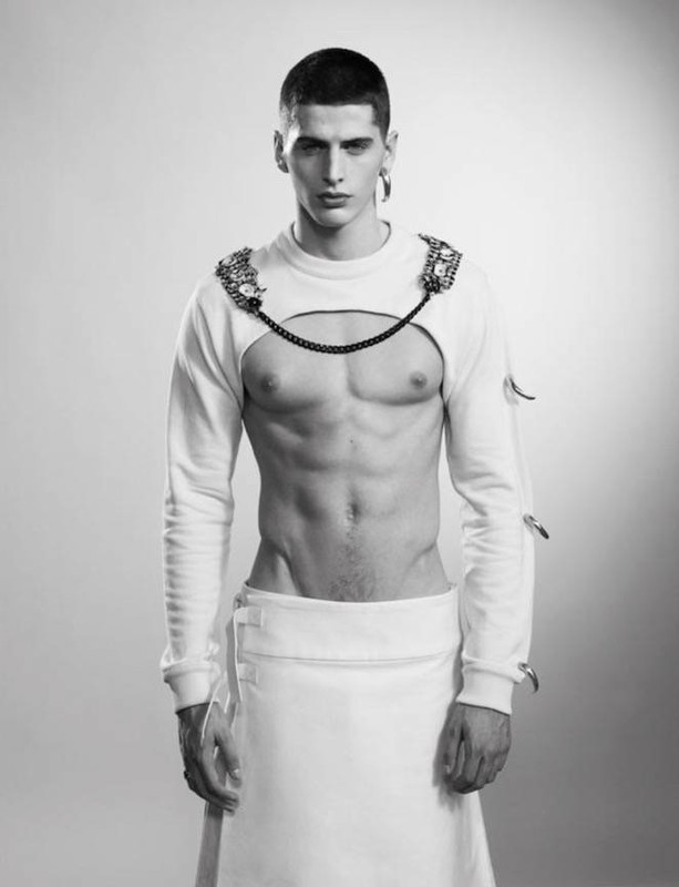 Portrait of a male model wearing a cut-out white top and skirt with hair styled by Colin Gold in Los Angeles.