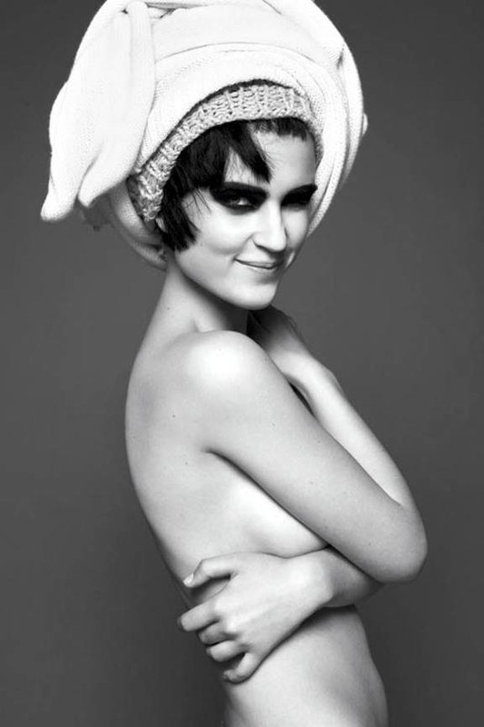 Black and white portrait of a woman with dark hair wearing a towel on her head and dark eye makeup against a grey background