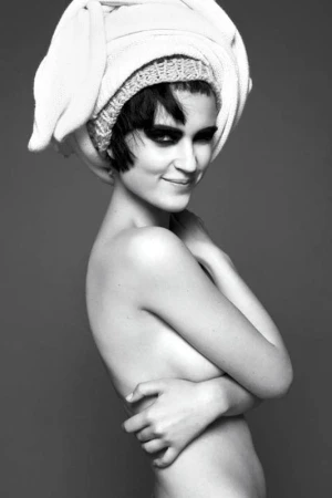 Black and white portrait of a woman with dark hair wearing a towel on her head and dark eye makeup against a grey background