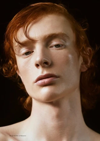Close-up portrait of a young man with red hair and fair skin against a dark background, styled by Colin Gold