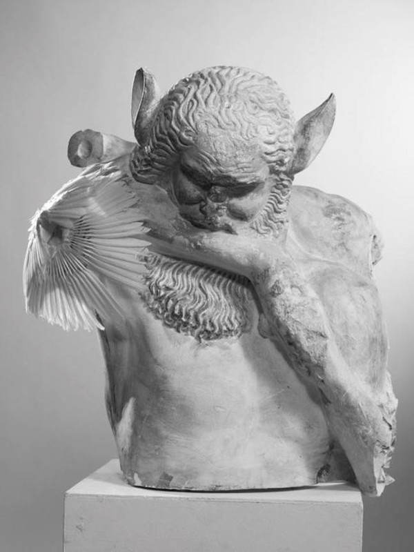 Monochrome image of a sculpture depicting a figure with animalistic features, posed on a pedestal in a bright, neutral setting.
