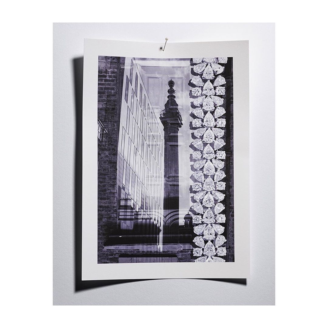 Monochromatic photograph of a print featuring a modern glass building juxtaposed with a classic stone structure and jewelry motifs.