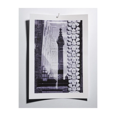 Monochromatic photograph of a print featuring a modern glass building juxtaposed with a classic stone structure and jewelry motifs.