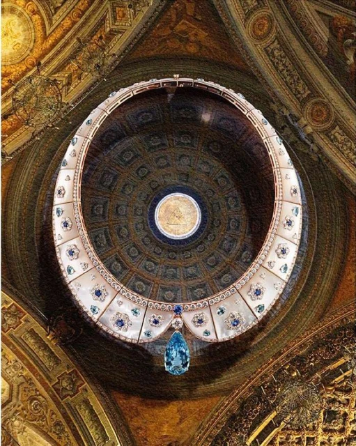 Elegant necklace featuring a teardrop aquamarine pendant and intricate gold filigree, displayed against an ornate, painted dome backdrop.
