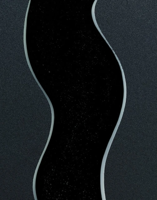 Abstract image of a black, river-like channel with subtle stars running vertically through a dark grey textured surface background.