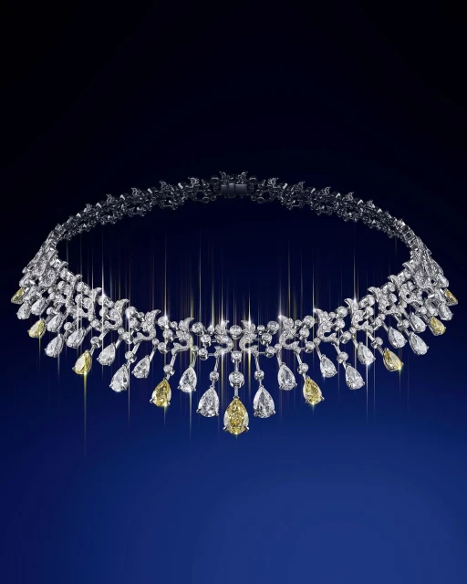 Elegant white gold necklace with yellow and white diamonds arranged in a floral pattern on a deep blue gradient background.