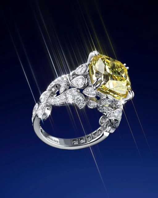 Close-up of a platinum ring featuring a large, square-cut yellow gemstone surrounded by smaller diamonds, highlighted by bright light flares.