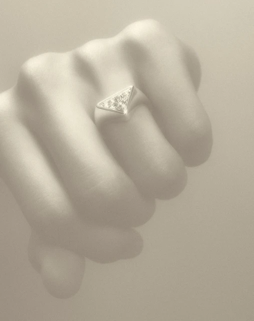 Close-up on a hand wearing a triangular ring. The ring is silver-colored, with a triangular design, and it's placed on the ring finger.