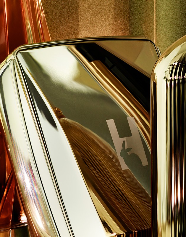Close-up of Hourglass brand makeup compact with the brand logo and the metal case reflecting light, showcasing gold color and textures.