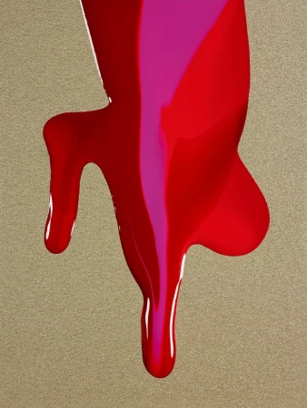 Abstract close-up of dripping red and pink paint on a textured gold surface, creating a vibrant and dynamic visual effect.