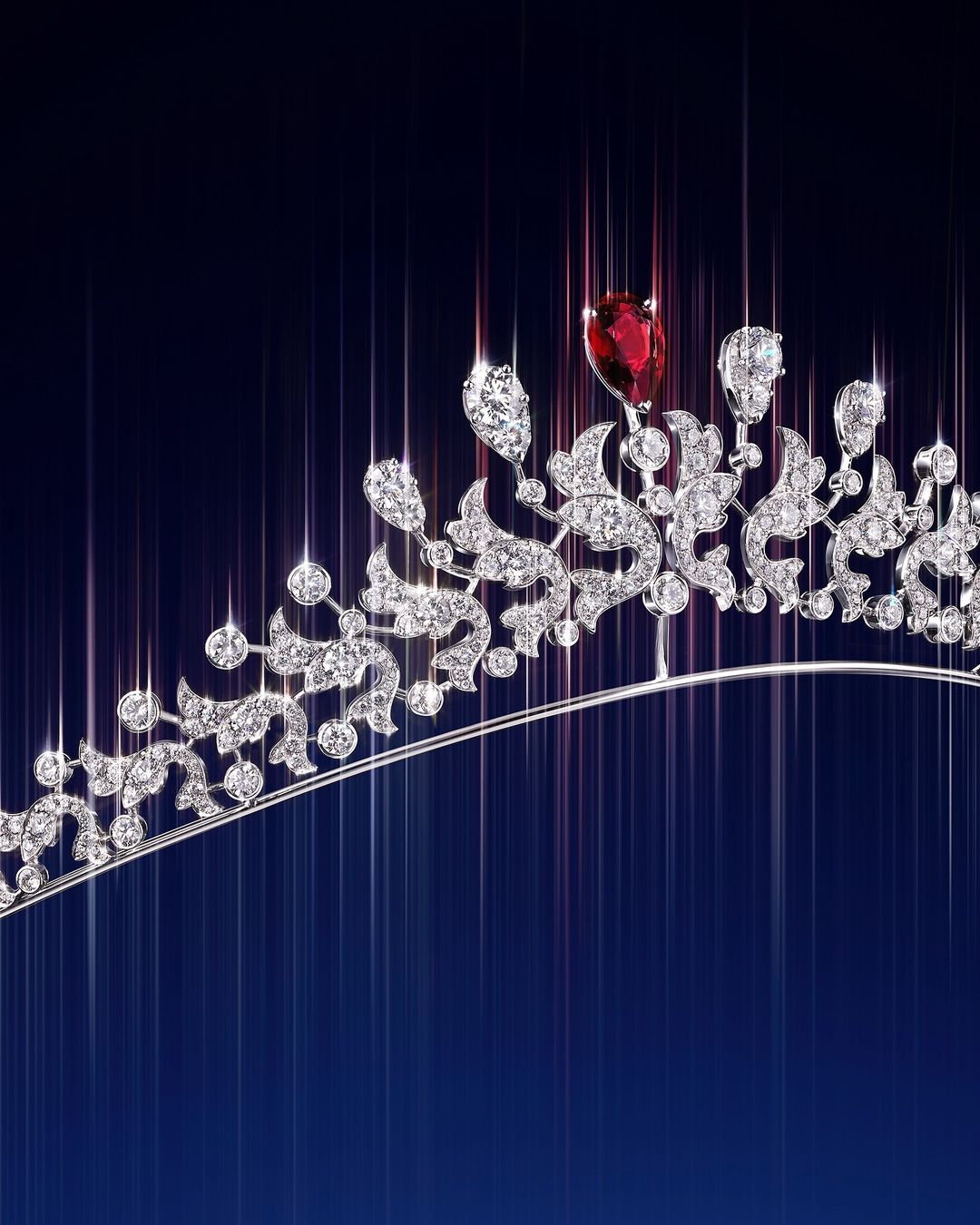 Close-up of an ornate tiara featuring diamonds and a ruby, displayed against a gradiated blue background with light streaks.
